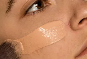 Ilustramos uma mulher passando base para pele da marca Avon, após pesquisar quais as melhores da marca