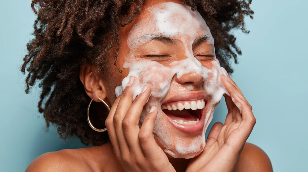 Ilustramos uma mulher sorrindo fazendo a preparação da sua pele